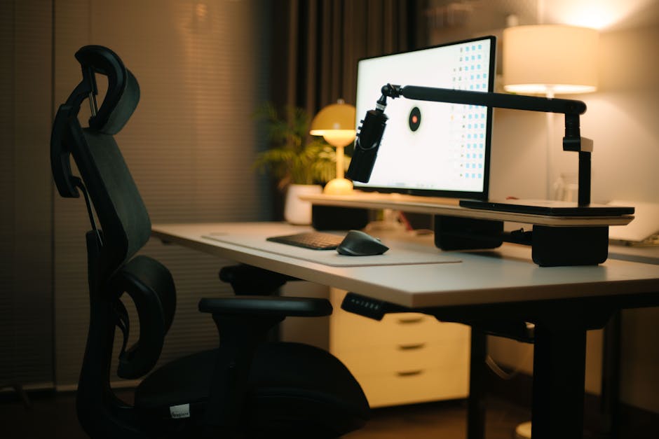 Modern hybrid office workspace with ergonomic desk setup, including supportive arm positioning to reduce strain for returning in-person workers
