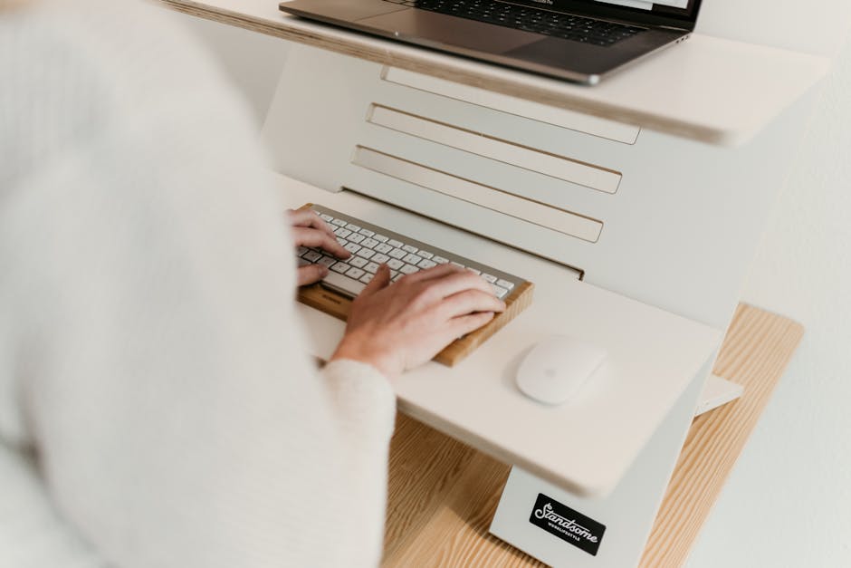 Professional ergonomic workspace with neutral wrist typing at laptop, aligned keyboard and mouse, showing pain-free productive office setup