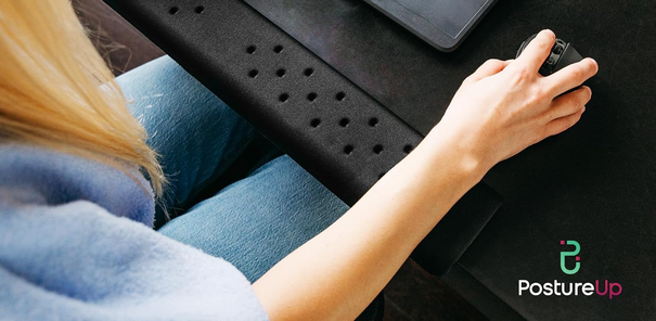 Person using a laptop with a black laptop stand, wearing blue jeans, on a dark surface.